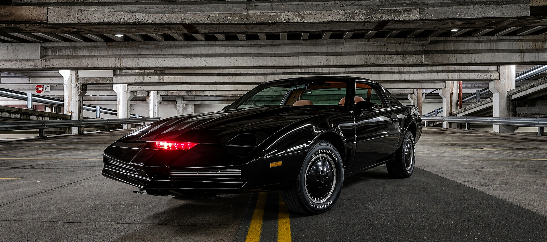 Front three-quarter view of the screen-accurate Knight Rider KITT replica parked in a concrete structure, showcasing the active red scanner light.