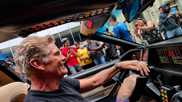 David Hasselhoff smiling behind the wheel of the KITT replica car during a cruise