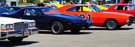 Side-by-side display of the 1982 KITT replica and the General Lee, celebrating two of the most iconic TV cars of the 1980s.